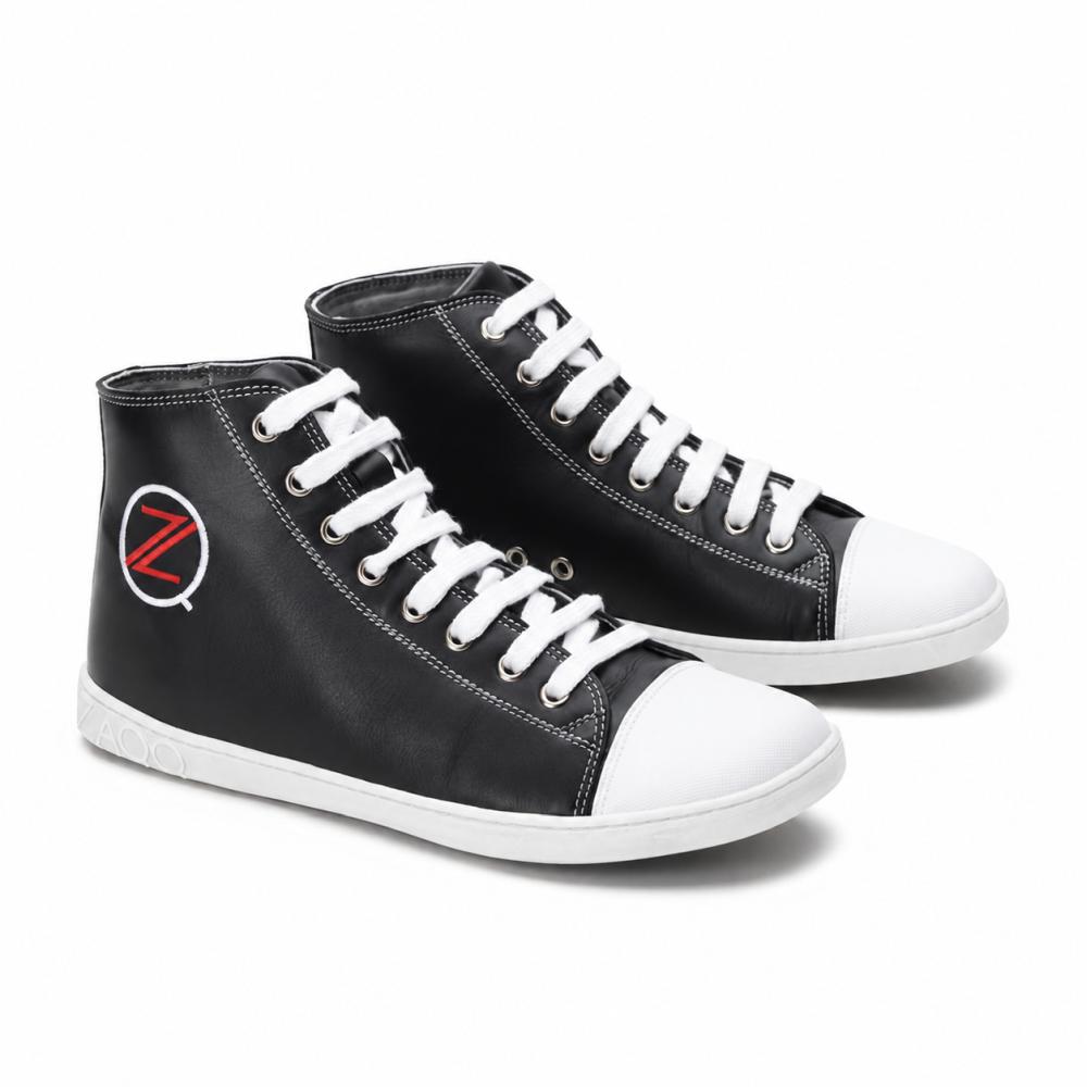 Un paio di classiche sneakers alte nere ZAQQ CHUQQS ha lacci bianchi e punte che mostrano ciascuna un vistoso logo Z rosso-bianco. Le suole sono fatte di gomma di caucciù resistente, conferendo alle scarpe un aspetto trendy e leggermente consumato.