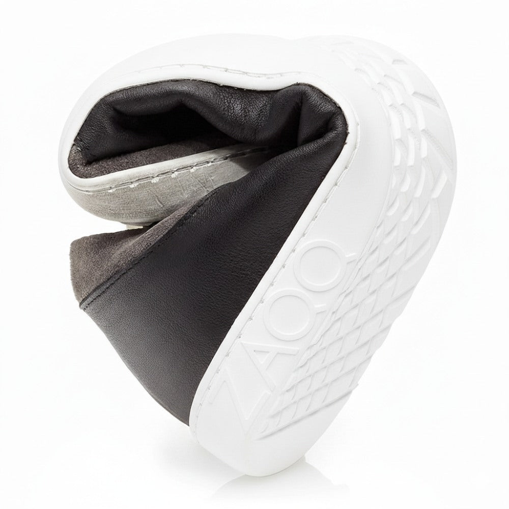 Die schwarze Schuhsohle QAANAAQ, die von ZAQQ aus leichten Materialien gefertigt wurde, ist gebogen und spiralförmig gerollt, um ihre Flexibilität hervorzuheben. Die Sohle mit geometrischem Muster trägt stolz das ZAQQ-Logo auf der Seite.