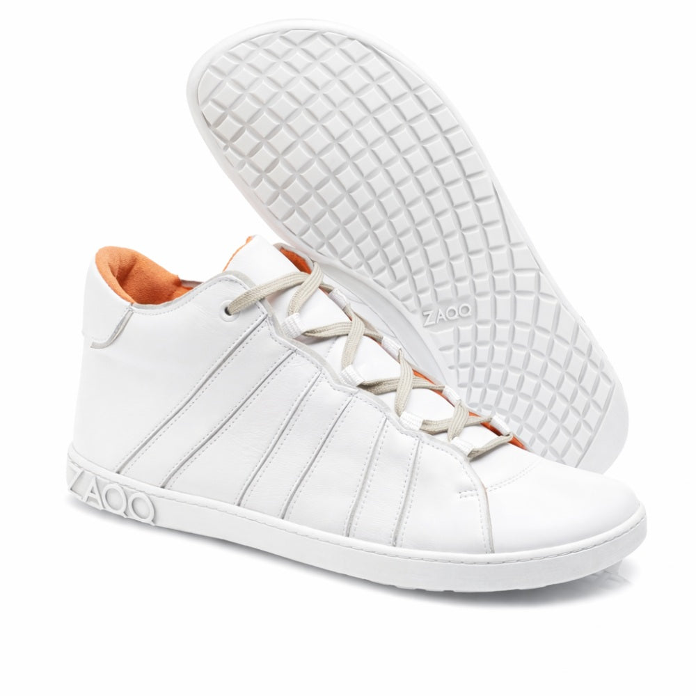 Der QQQ Mid White von ZAQQ ist ein Paar weißer High-Top-Sneaker aus hochwertigem Nappaleder mit orangefarbenem Innenfutter und grauer Sohle. Ein Schuh steht aufrecht, während der andere sich neigt und seine Barfußschuhsohle mit Waffelmuster zeigt. Der Markenname ZAQQ ist elegant auf der Seite und der Sohle angebracht und unterstreicht ihr stilvolles Design.