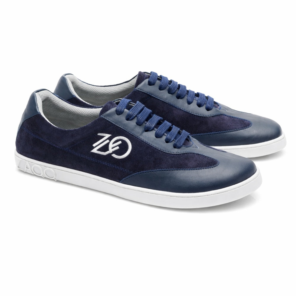 Der Queensburry Marine von ZAQQ ist ein Barfuß-Sneaker in Marineblau aus Wildleder und dunkelblauem Leder, verziert mit einer eleganten weißen Stickerei an der Seite. Diese Schuhe sorgen mit ihrer weißen Sohle und den passenden blauen Schnürsenkeln für Komfort beim Laufen.