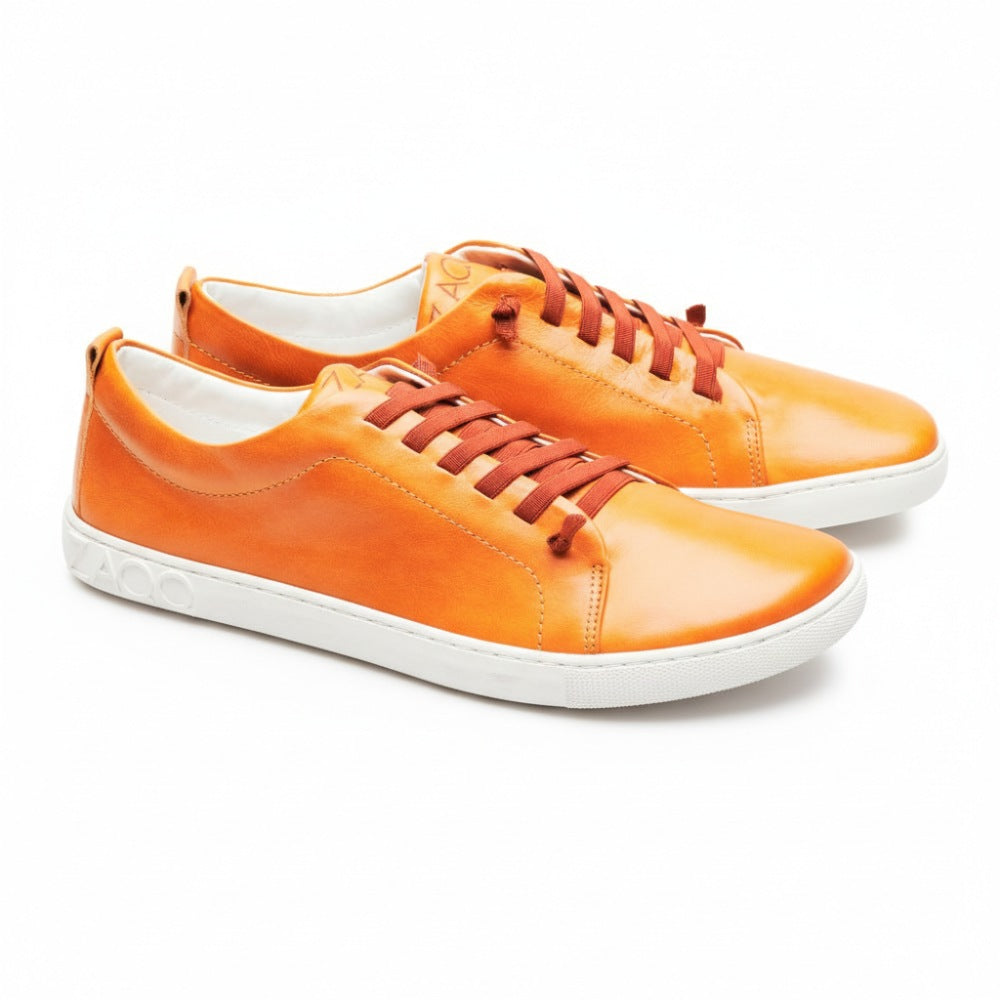 Ein Paar leuchtend orangefarbene STIQ Sierra-Sneaker mit weißer Sohle und orangefarbenen Schnürsenkeln. Die Schuhe, die an der Ferse mit der Marke ZAQQ versehen sind, sind schräg positioniert, um ihr schlankes Design und ihre auffällige Farbe hervorzuheben.